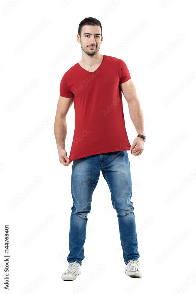 Young man stretching and showing red t-shirt blank copy space. Full body length portrait isolated over white studio background. Young man stretching and showing red t-shirt blank copy space. Full body length portrait isolated over white studio background.