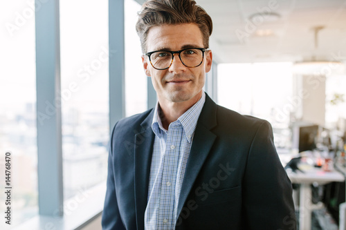 Confident mature businessman standing in office