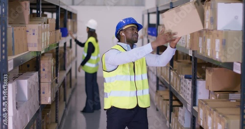  Worker in industrial warehouse, listening to music and dancing as he works