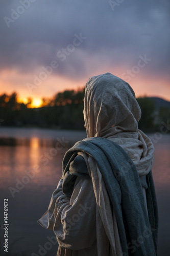 Jesus Christ looking over a lake during a sunset