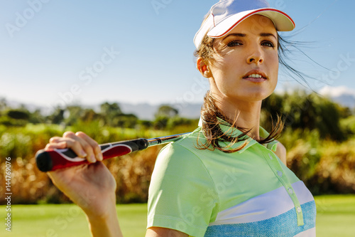 Young woman standing on golf course.