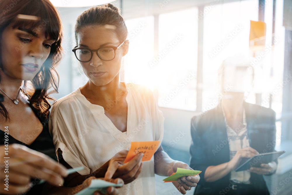 Professionals using adhesive notes for brainstorming Professionals using adhesive notes for brainstorming