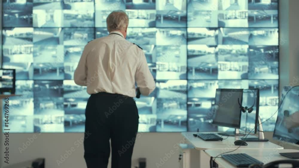 Security officer alone in observation control room does a little dance while no-one's watching. Security officer alone in observation control room does a little dance while no-one's watching.
