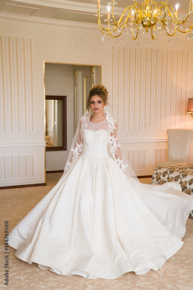 Portrait of beautiful young bride. A girl is posing in a hotel room. A lady Is worth with by the window. bride waiting in hotel. Portrait of beautiful young bride. A girl is posing in a hotel room. A lady Is worth with by the window. bride waiting in hotel.
