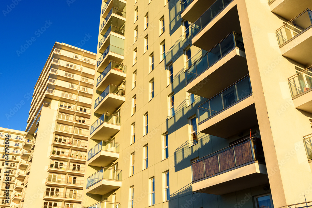 Obraz premium Modern apartment block with balcony against a blue sky.