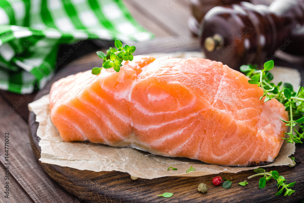 Raw salmon fish fillet on wooden board closeup Raw salmon fish fillet on wooden board closeup