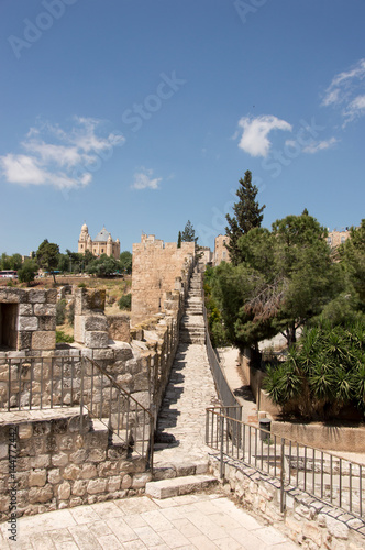 Path or walk way on the wall of the old city of Jerusalem with the Dormition Abbey in the background. And trees and bushes near the wall