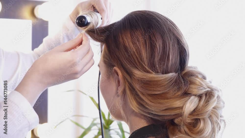 Hairdresser creating a hairstyle for a brunette woman in hair salon Hairdresser creating a hairstyle for a brunette woman in hair salon