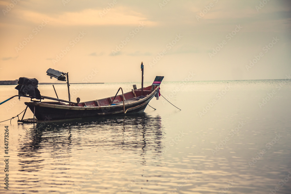 Tranquil sea scenery with traditional floating asian boat during sunset