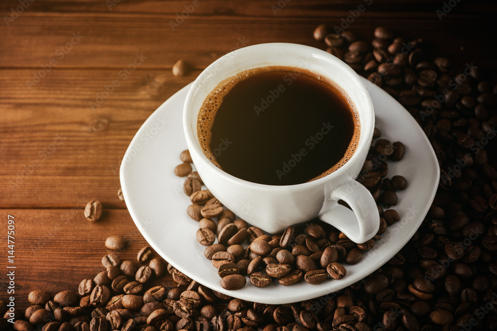 Coffee cup with saucer and beans on wooden table. Coffee cup with saucer and beans on wooden table.
