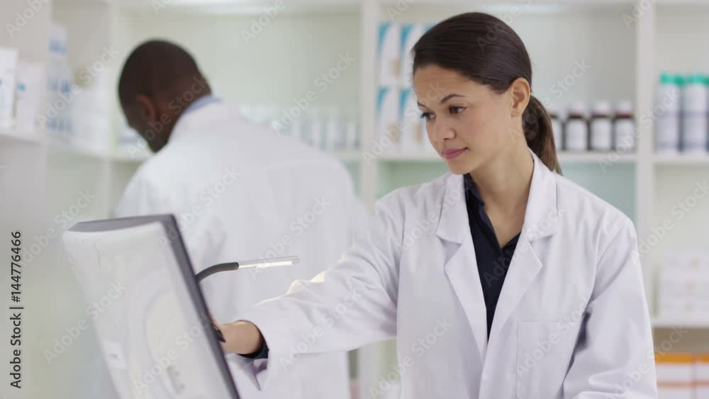 Workers in a chemist shop checking stock & looking at computer Workers in a chemist shop checking stock & looking at computer