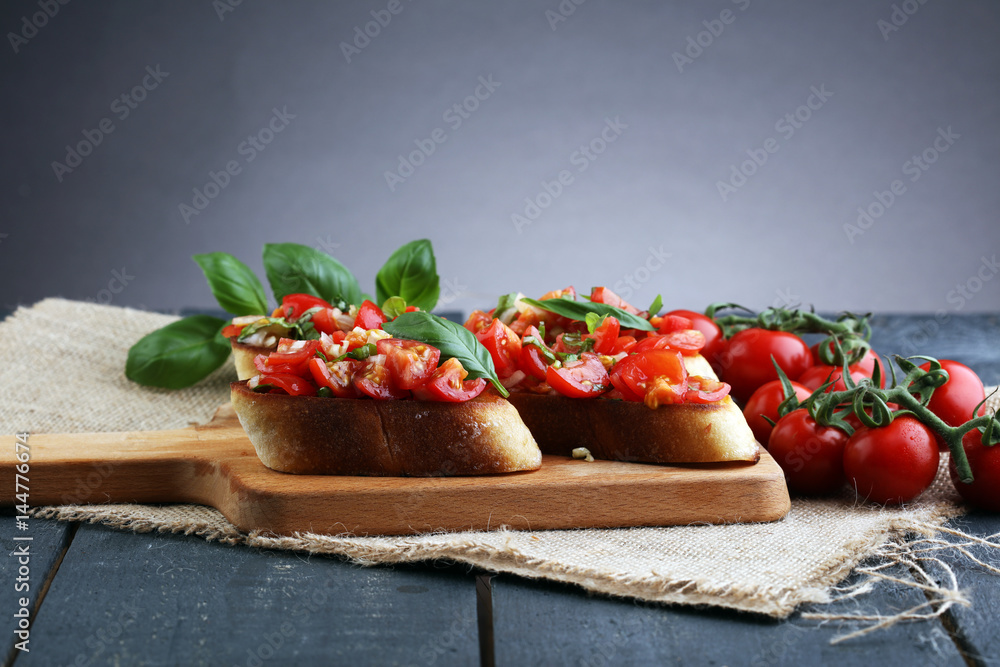 Tasty savory tomato Italian appetizers, or bruschetta, on slices of toasted baguette garnished with basil Tasty savory tomato Italian appetizers, or bruschetta, on slices of toasted baguette garnished with basil