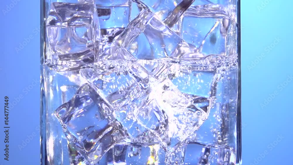 Water is pouring into a glass with ice cubes. Clear water pours ice cubes on a blue background. Pure water with Ice and bubbles in glass. Full HD footage 1920x1080p. Slow motion 240 fps Water is pouring into a glass with ice cubes. Clear water pours ice cubes on a blue background. Pure water with Ice and bubbles in glass. Full HD footage 1920x1080p. Slow motion 240 fps