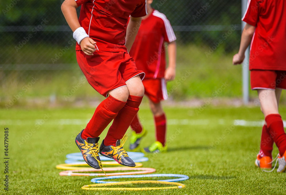 Naklejka premium Young Soccer Player Practicing on the Pitch. Soccer Football Equpment. Dynamic Jumping Football Training