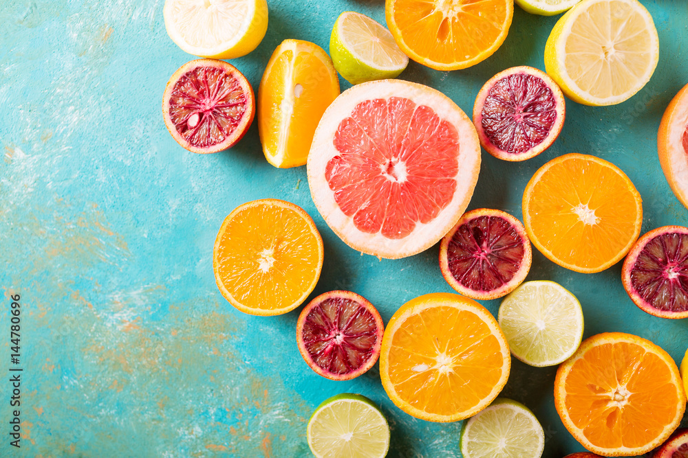Fototapeta Cytrus owoc na turkusowym abstrakcjonistycznym tle. Оrange, cytryna, grejpfrut, mandarynka, limonka. Mieszane świąteczne kolorowe owoce tropikalne i cytrusowe w plasterkach. Zdrowe jedzenie koncepcja zdjęć. Copyspace