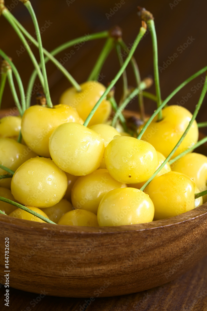 Ripe yellow or Rainier cherry in wooden bowl, photographed with natural light (Selective Focus, Focus one third into the cherries)