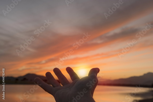 Catching the sun with his hand on the lake at sunset