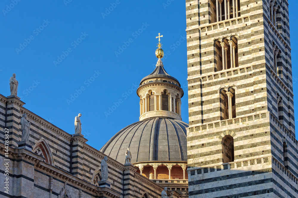 Dome and Bell Tower of the Cathedral Duomo of Siena lit by the afternoon sun - Siena, Italy