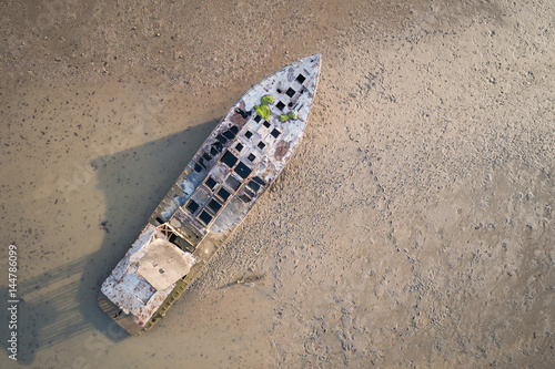 Old fishing boat standing in the mud sea. Aerial view from flying drone