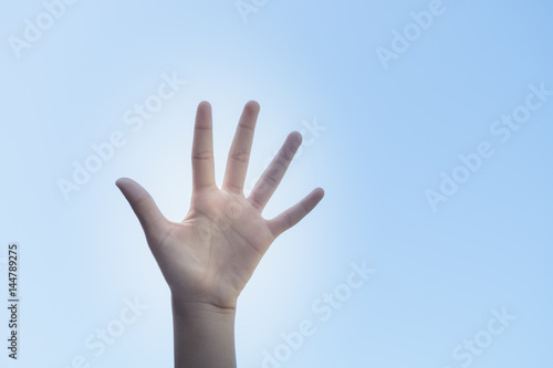 Closeup hand in the air against a clear sunny blue sky in a conceptual image with copy space