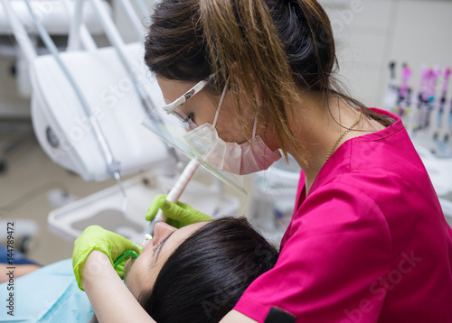 Photography Female dentist cleaning teeth of a beautiful patient woman in dental clinic