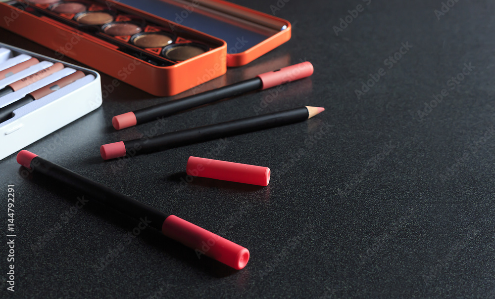 makeup cosmetics on black table background, over light, top view makeup cosmetics on black table background, over light, top view