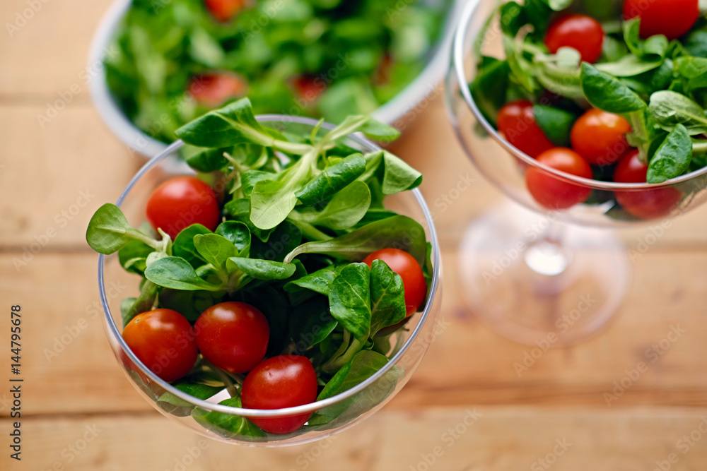 Cherry tomatoes and basil salad on a glass cup on a wooden table. Cherry tomatoes and basil salad on a glass cup on a wooden table.