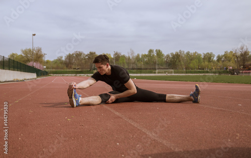 one young man, stretching leg, running tracks