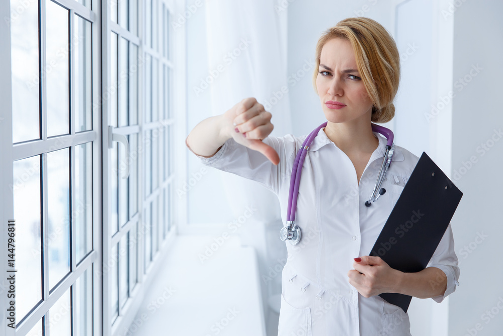 Closeup portrait, doctor woman, giving thumbs down gesture Closeup portrait, doctor woman, giving thumbs down gesture