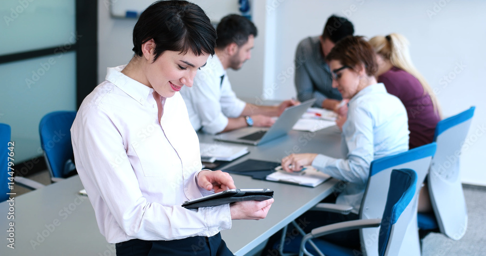 Portrait of  smiling casual businesswoman using tablet  with coworkers standing in background