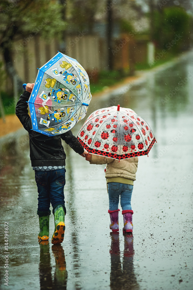 children walk in the rain holding umbrellas
