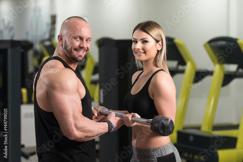 Woman Exercising Biceps With Her Personal Trainer