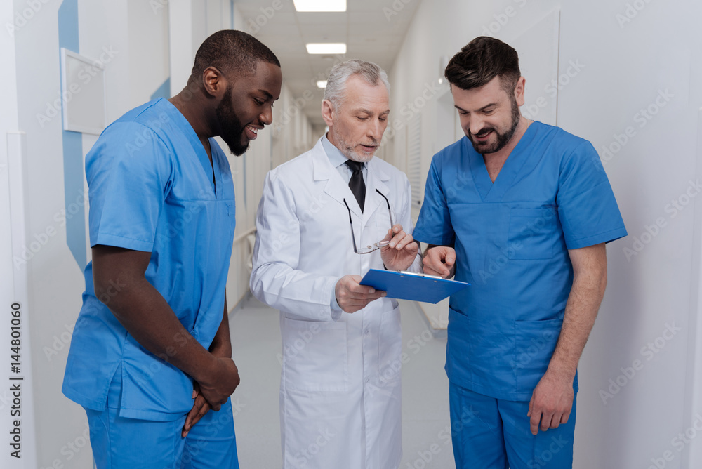 Obraz premium Optimistic aging pediatrician consulting young doctors in the clinic