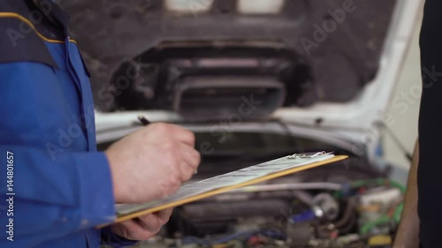 Close up of hands client of repair car service is giving keys to car mechanic with clipboard and shaking hands photo