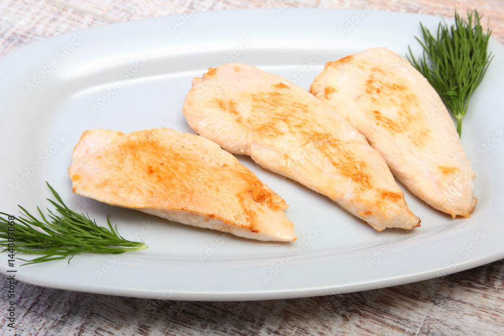 Slices of roasted chicken breast and tomato on white plate Slices of roasted chicken breast and tomato on white plate