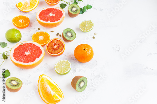 Fruit background. Colorful fresh fruit on white table. Orange  tangerine  lime  kiwi  grapefruit