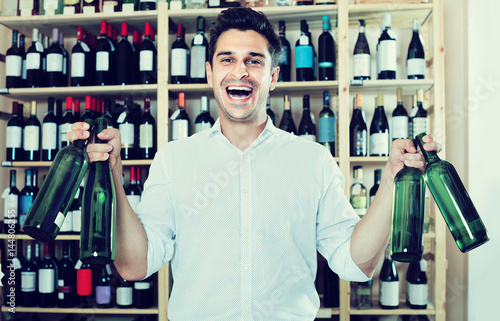 portrait of man choosing bottle of wine in shop