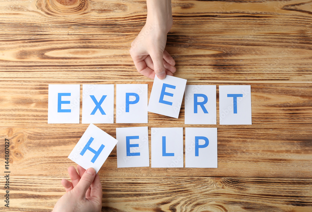 Female hands and phrase EXPERT HELP on wooden background Female hands and phrase EXPERT HELP on wooden background
