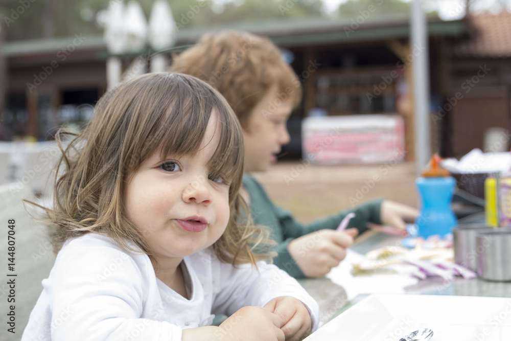 little girl sitting at restaurant table next to her brother little girl sitting at restaurant table next to her brother