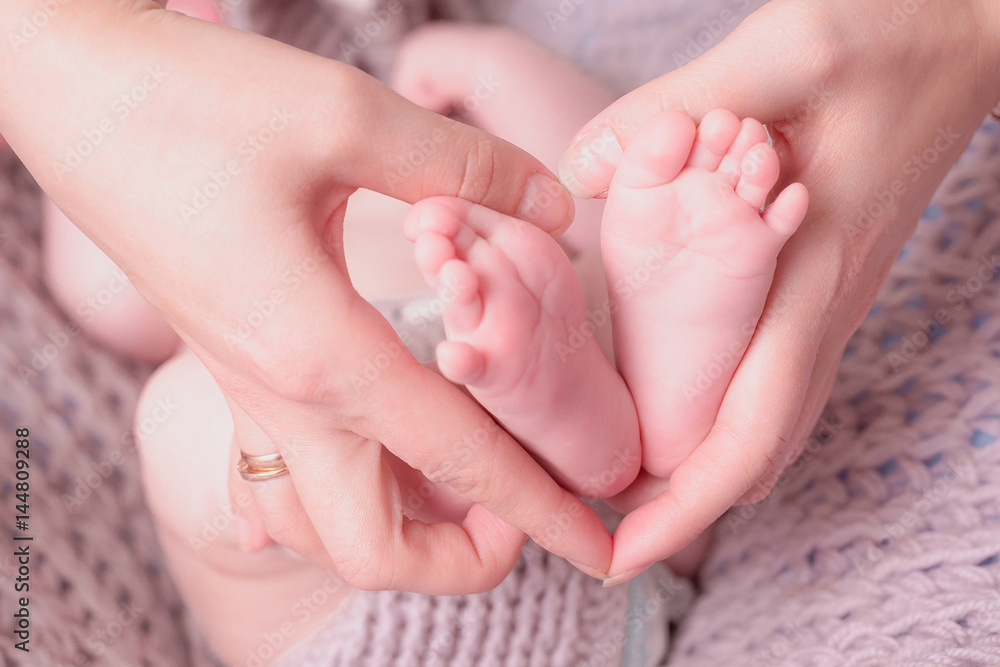Baby feet in mother hands. Tiny Newborn Baby's feet on female Shaped hands closeup. Mom and her Child. Baby feet in mother hands. Tiny Newborn Baby's feet on female Shaped hands closeup. Mom and her Child.