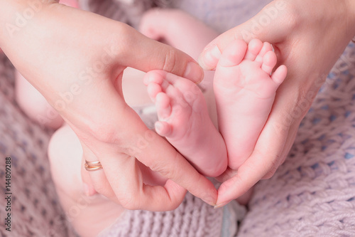 Baby feet in mother hands. Tiny Newborn Baby's feet on female Shaped hands closeup. Mom and her Child. © Lyubov