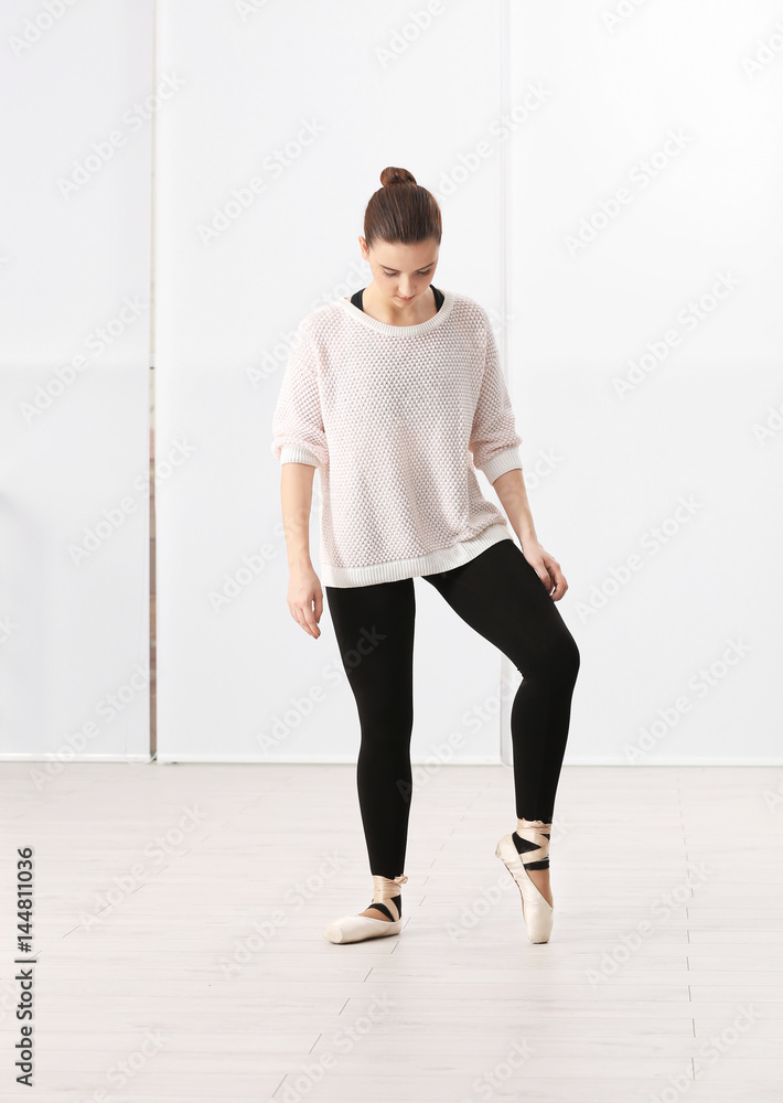 Fototapeta premium Ballet art concept. Young beautiful ballerina training in dance hall