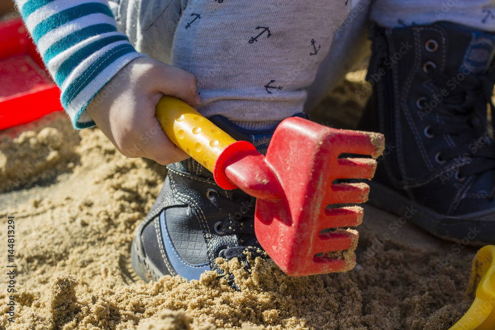 Child playing with plastic rakes on sandbox. Child playing with plastic rakes on sandbox.