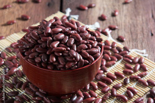 Red beans in a cup with a wooden sign on the wooden floor.