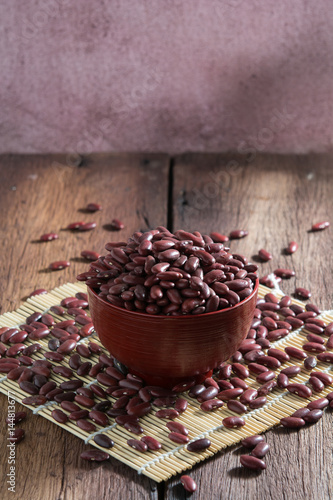 Red beans in a cup with a wooden sign on the wooden floor.