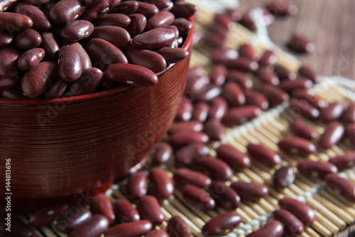 Red beans in a cup with a wooden sign on the wooden floor.