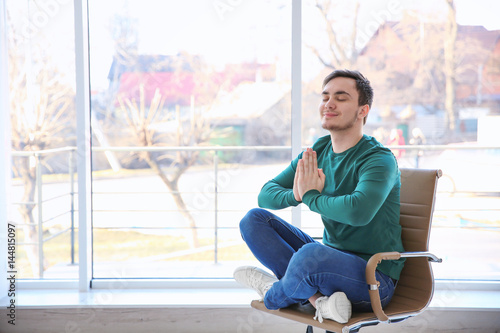 Free Download Happy young man sitting on chair and meditating - GFXLoad