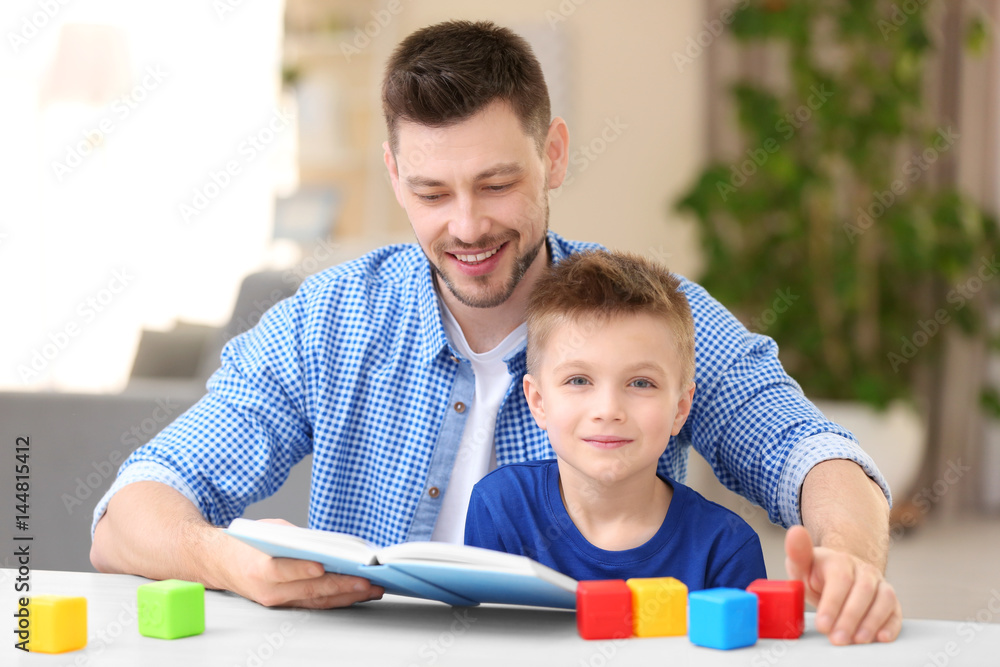 Obraz premium Dad and son reading interesting book at home