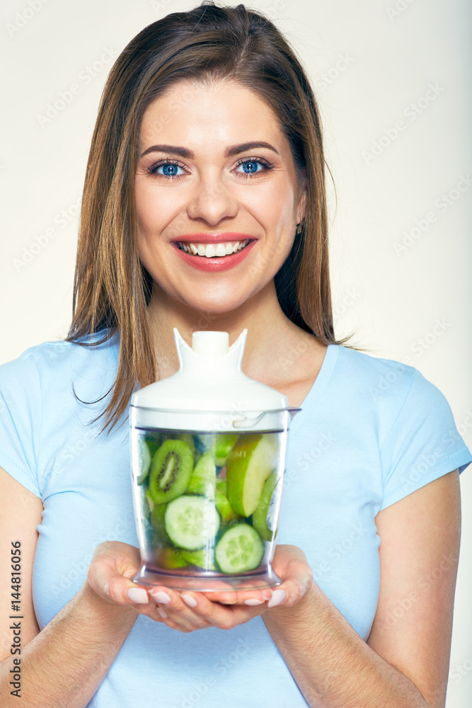 Smiling young woman holding blender with green smoothy ingredients. Smiling young woman holding blender with green smoothy ingredients.