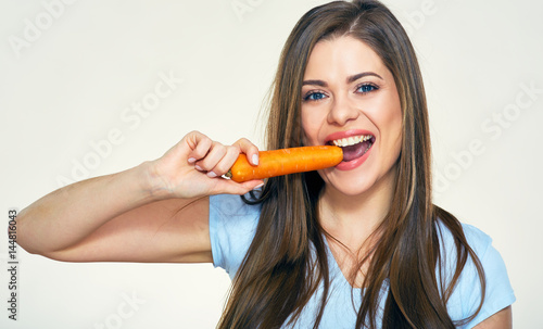 Smiling woman bites carrot. Isolated studio portrait.